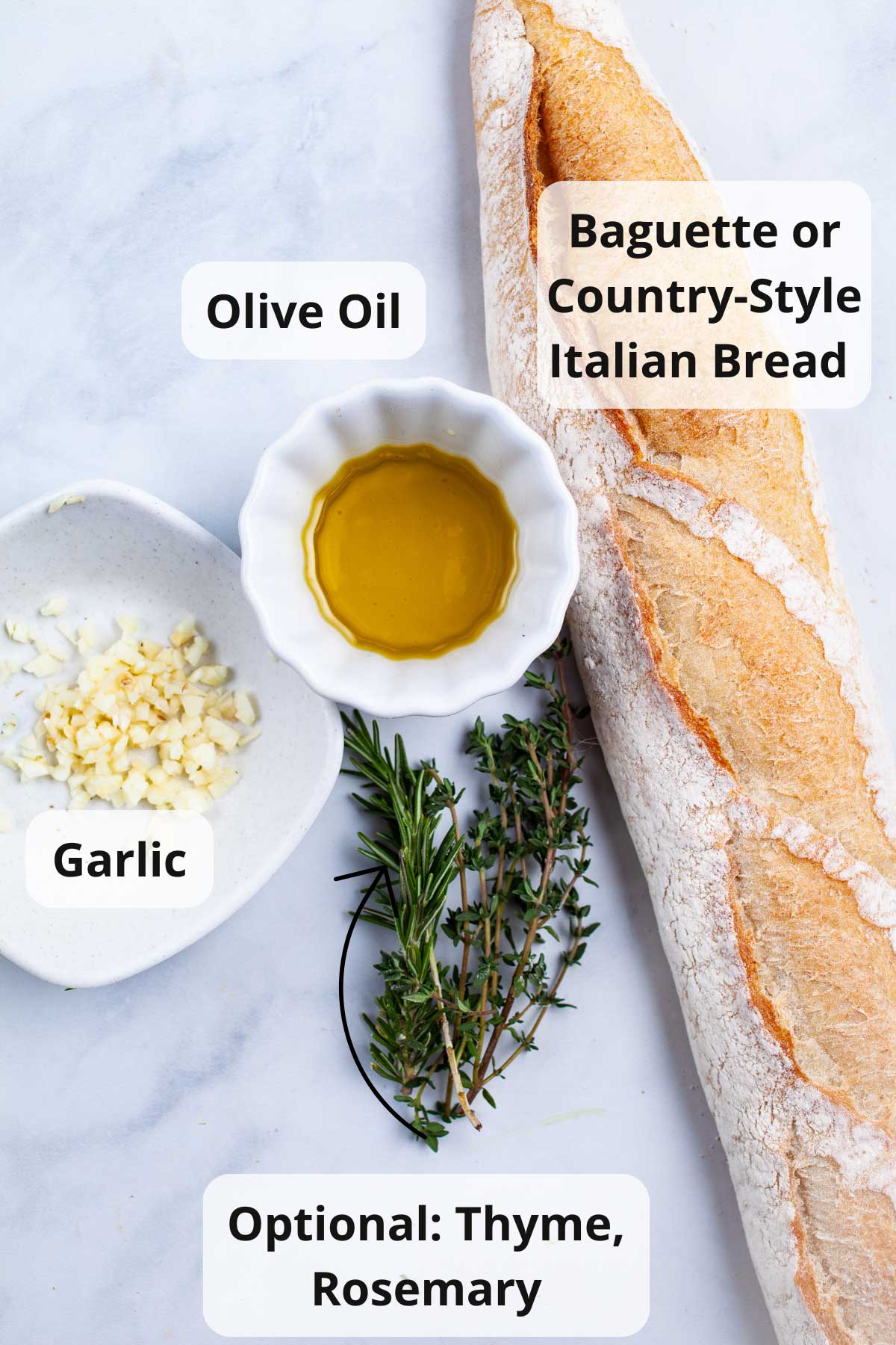 Ingredients: Olive oil, baguette, garlic, thyme, rosemary to make garlic crostini displayed on a table.