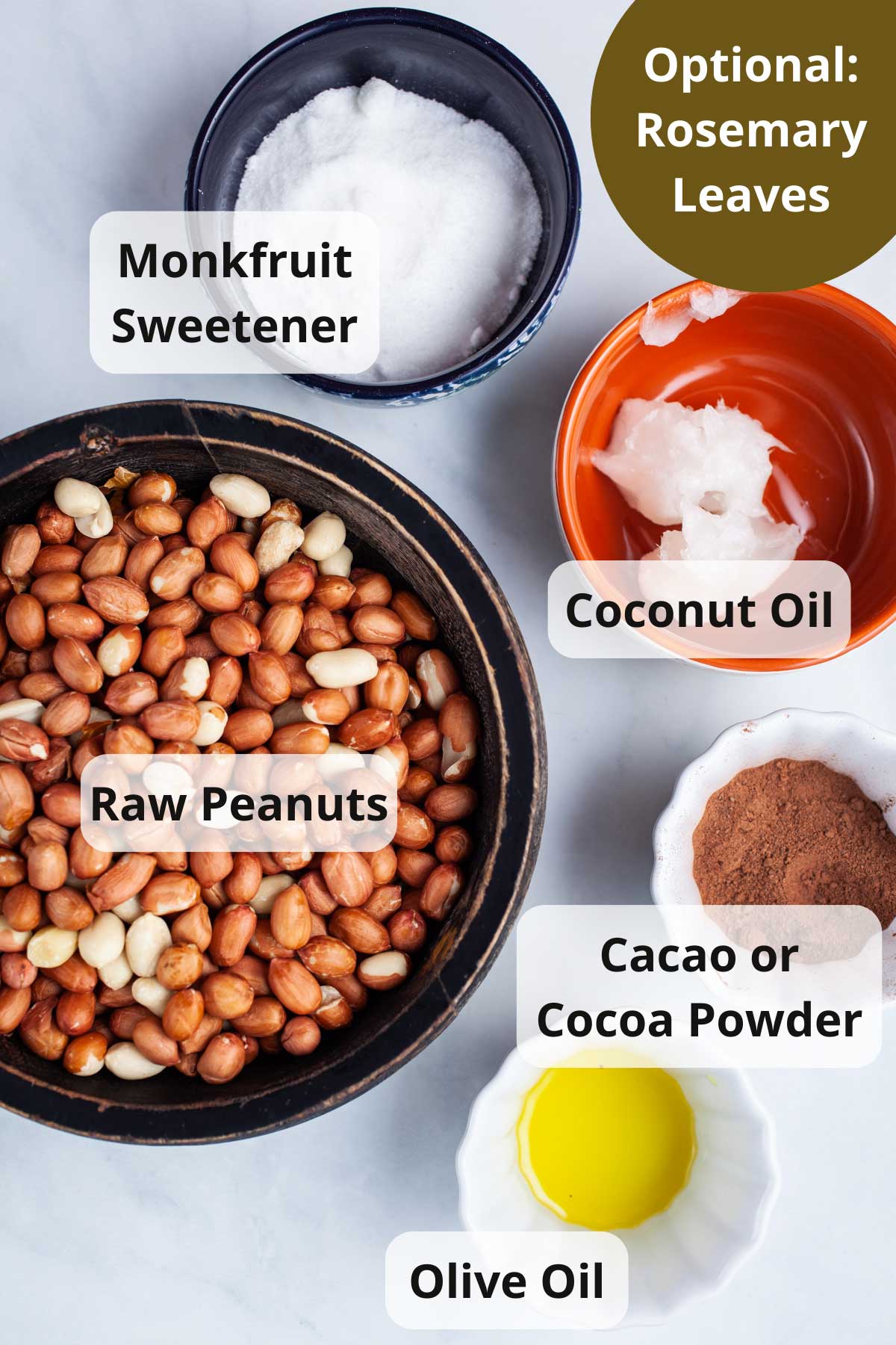 Raw peanuts, Monkfruit sweetener, coconut oil, cacao powder, olive oil, and coconut oil displayed on a table.