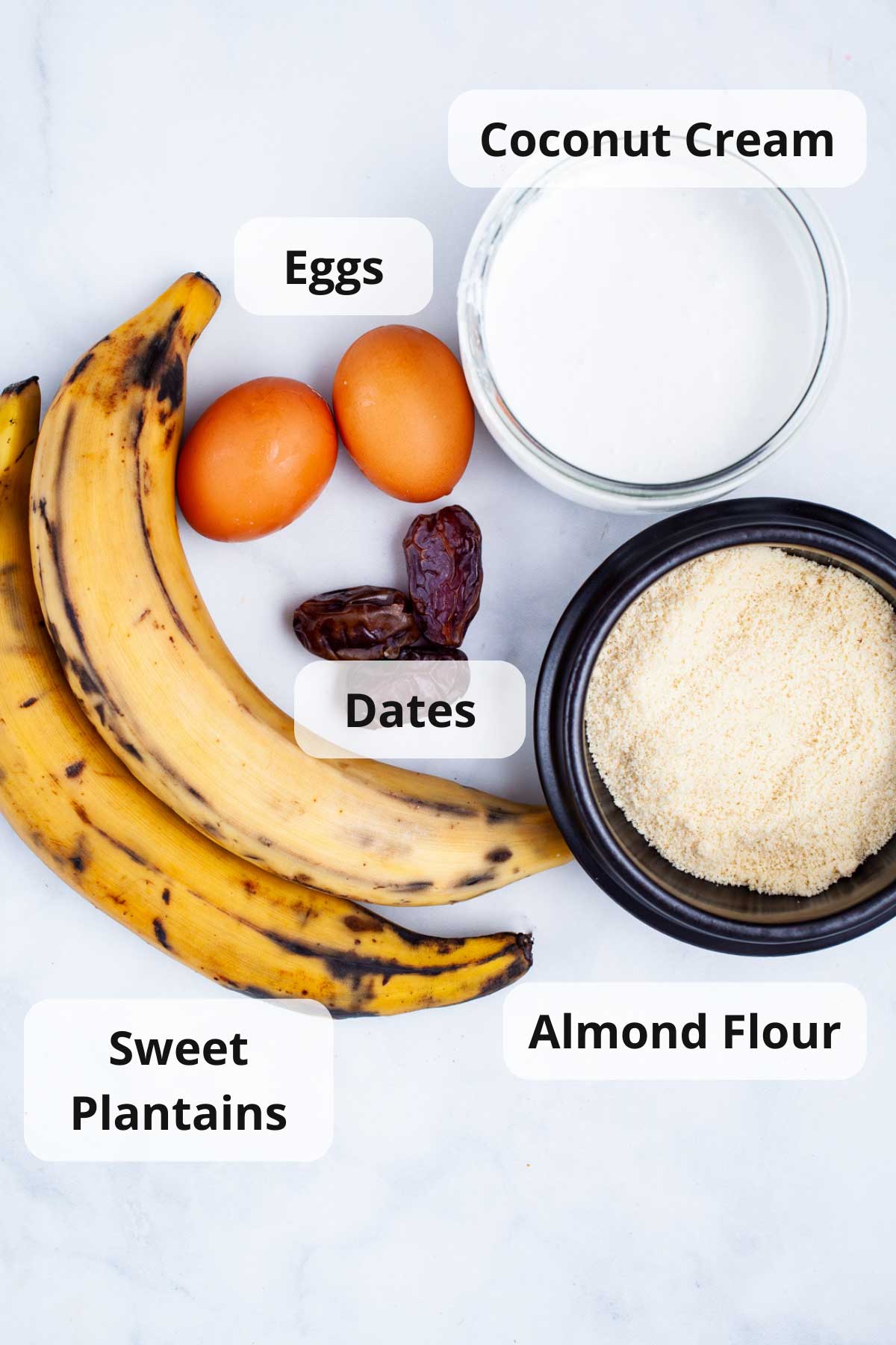 Coconut cream, eggs, sweet plantains, dates, and almond flour displayed on a table.