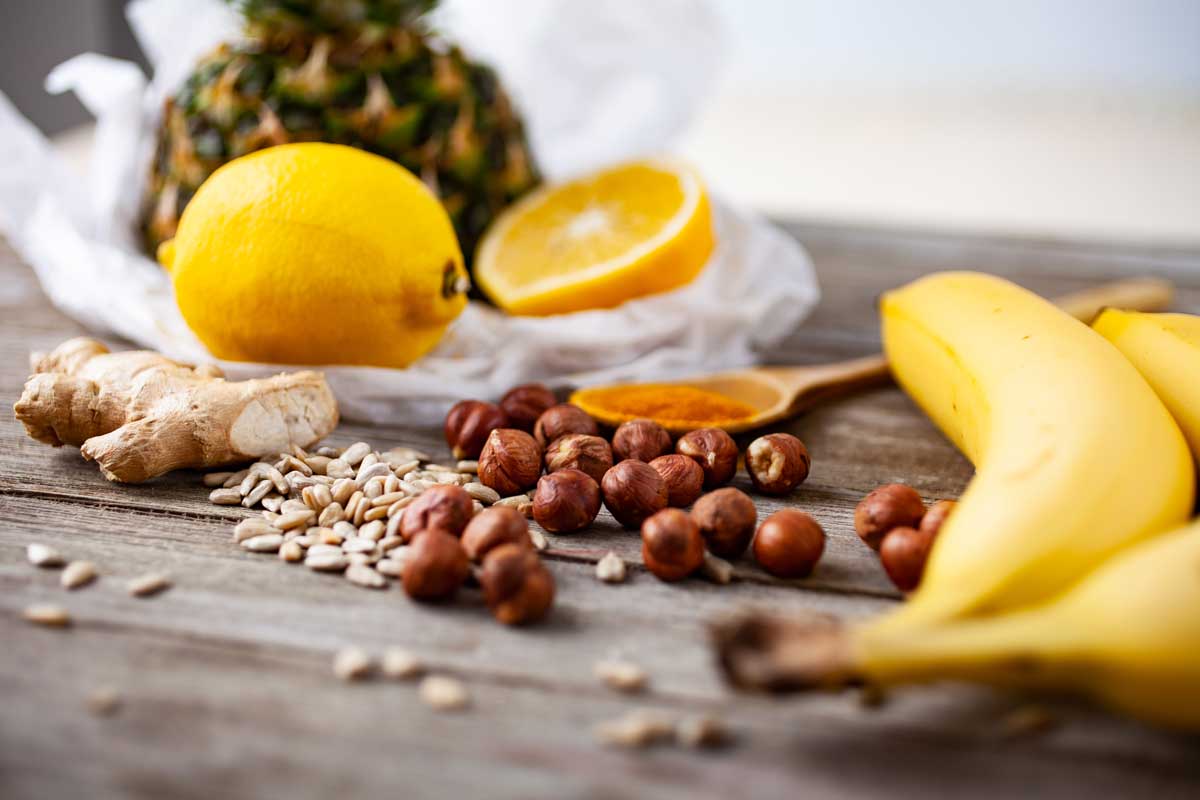 Ingredients like lemon, banana, pineapple, turmeric, ginger, hazelnuts and seeds for making a healthy creamy smoothie