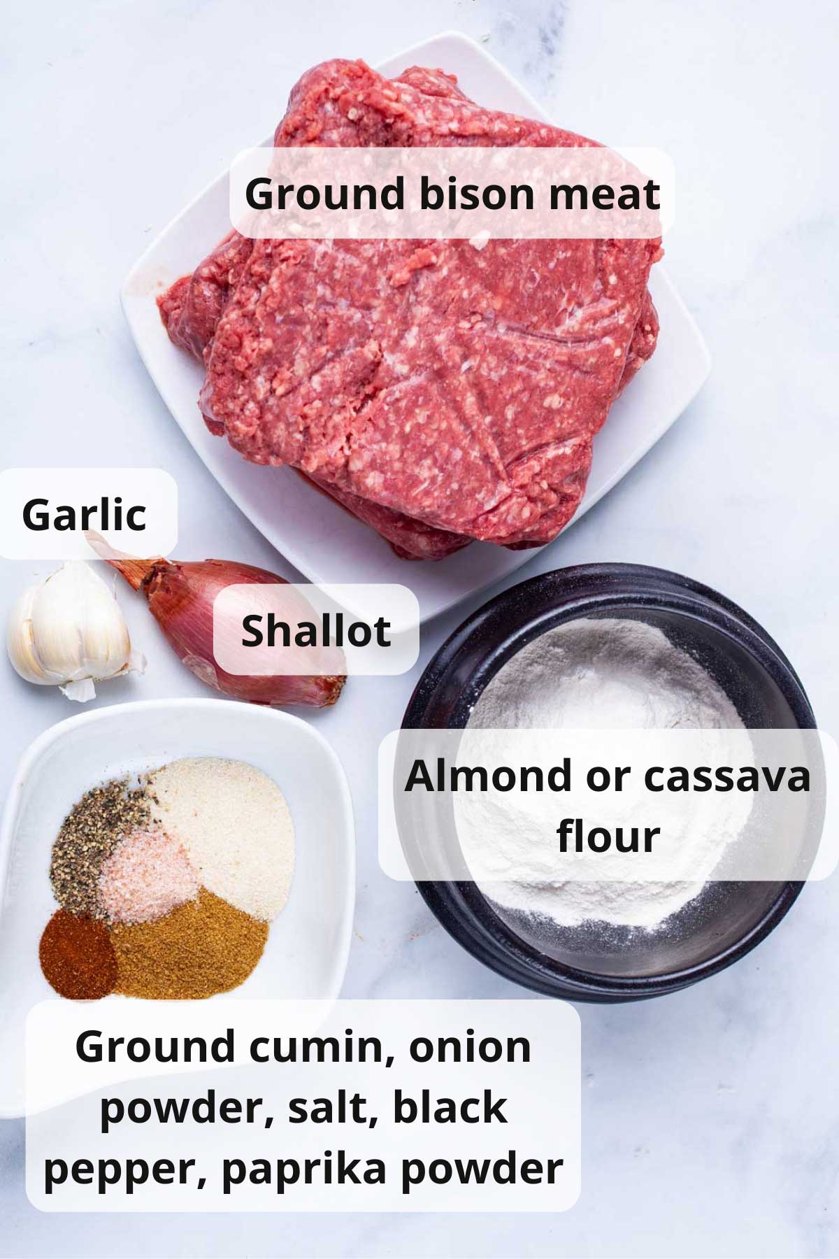 Ground bison meat, Cassava flour, ground cumin, onion powder, salt, pepper, paprika powder, shallot, and garlic displayed on a table.