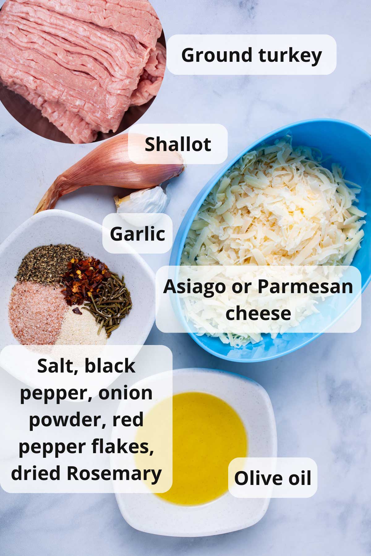 Grated cheese, one shallot, garlic, ground turkey, olive oil, and seasoning displayed on a table.