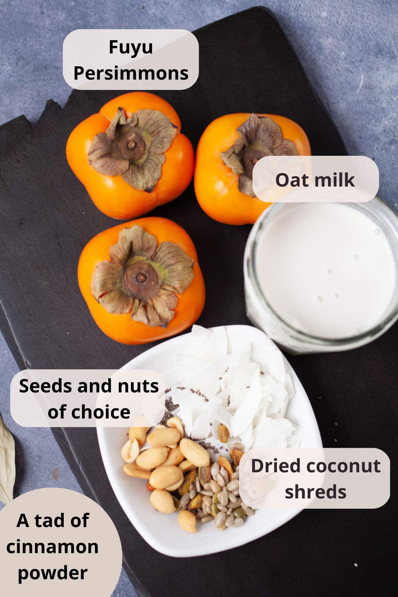 Ingredients like Fuyu persimmons, oat milk, dried coconut shreds, seeds and nuts displayed on a serving board.