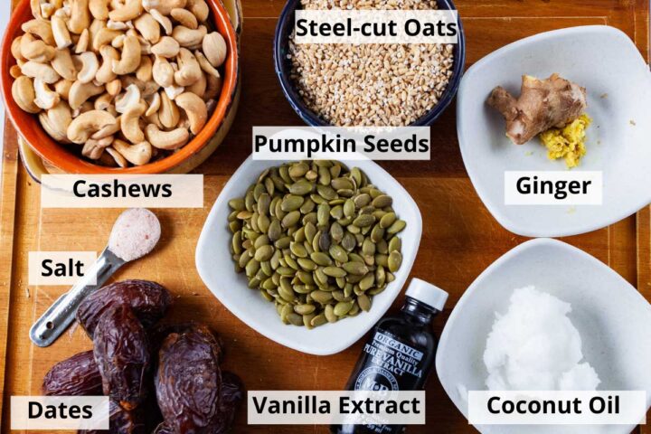 Ingredients to create a no-bake tart crust on a cutting board: cashews, steel-cut oats, fresh ginger, pumpkin seeds, salt, Medjool dates, vanilla extract, and coconut oil.