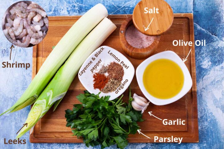 Shrimp, leeks, parsley, garlic, olive oil, salt, cayenne and black pepper, lemon peel, and dried oregano, all ingredients shown to make a garlic shrimp dish.