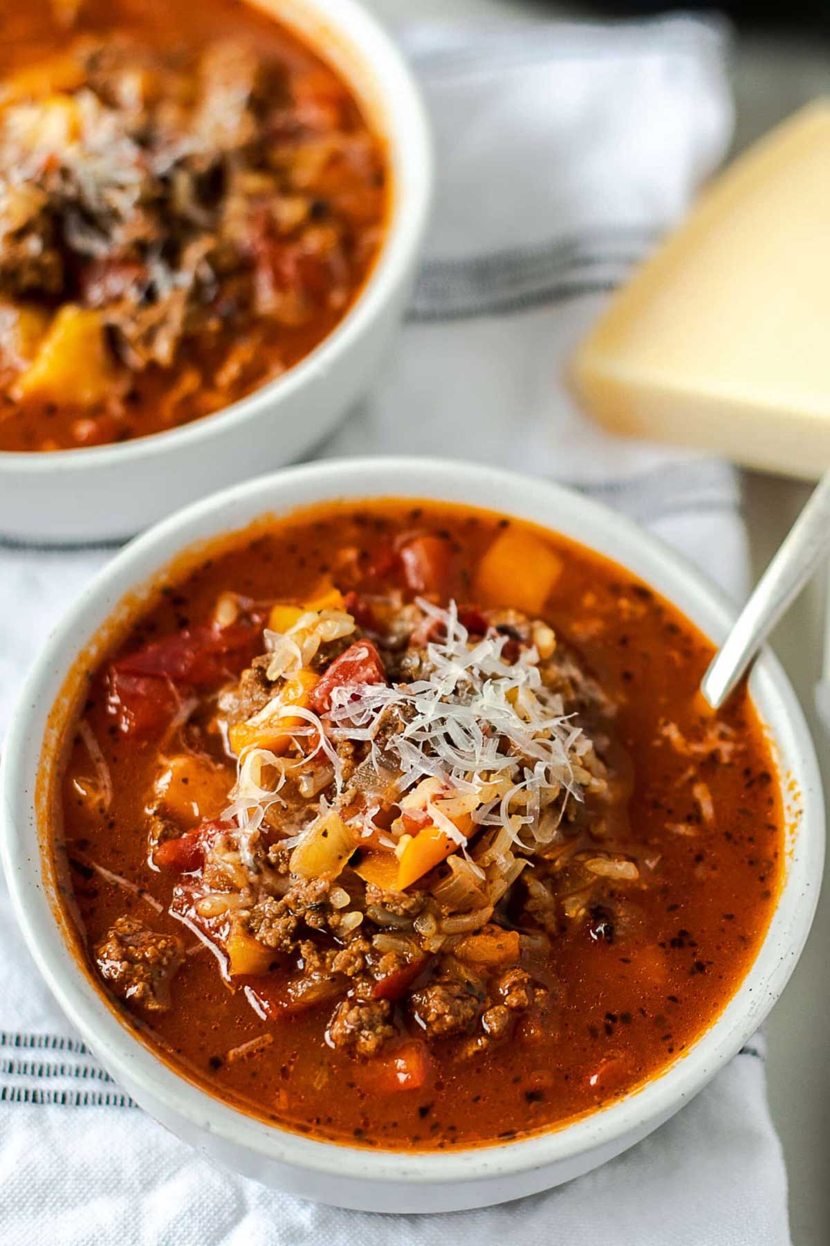 Stuffed pepper soup in a small bowl topped with grated cheese.