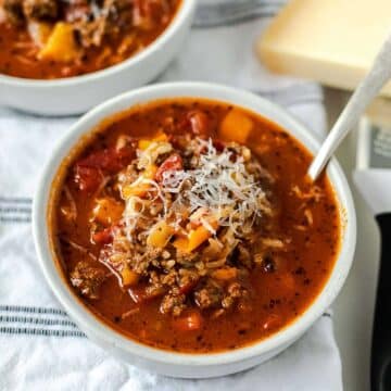 Stuffed pepper soup in a small bowl topped with grated cheese.