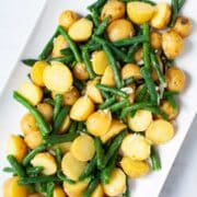 Olive oil coated mini potatoes and green beans on a serving plate.