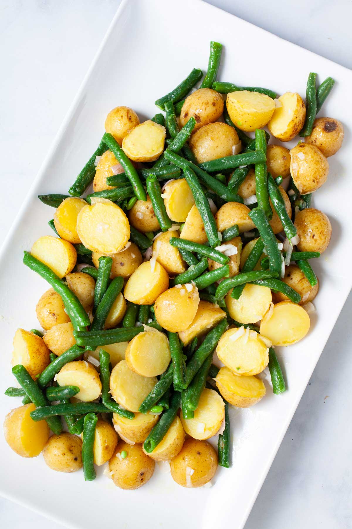 Olive oil coated mini potatoes and green beans on a serving plate.