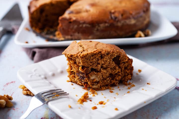 Half of a coffee cake resting on a small platter with the rest of the cake in the background.