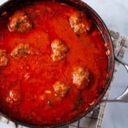 A large pot containing an Italian red sauce with beef meatballs.