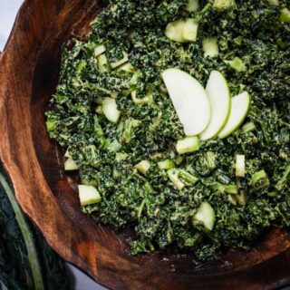 A massaged apple kale salad in a large wooden bowl.