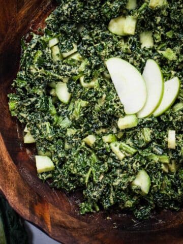 A massaged apple kale salad in a large wooden bowl.