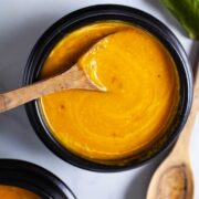 A spoon resting in a bowl with creamy Kabocha soup.