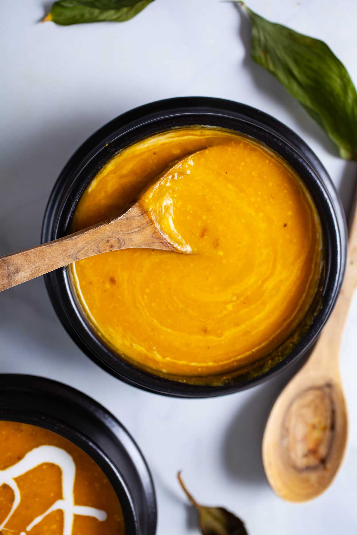 A spoon resting in a bowl with creamy Kabocha soup.