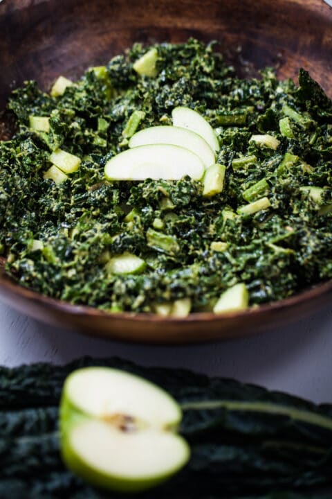 A massaged apple kale salad in a large wooden bowl.