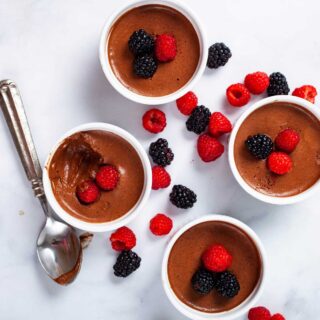 Four ramekins filled with chocolate mousse and topped with fresh berries.