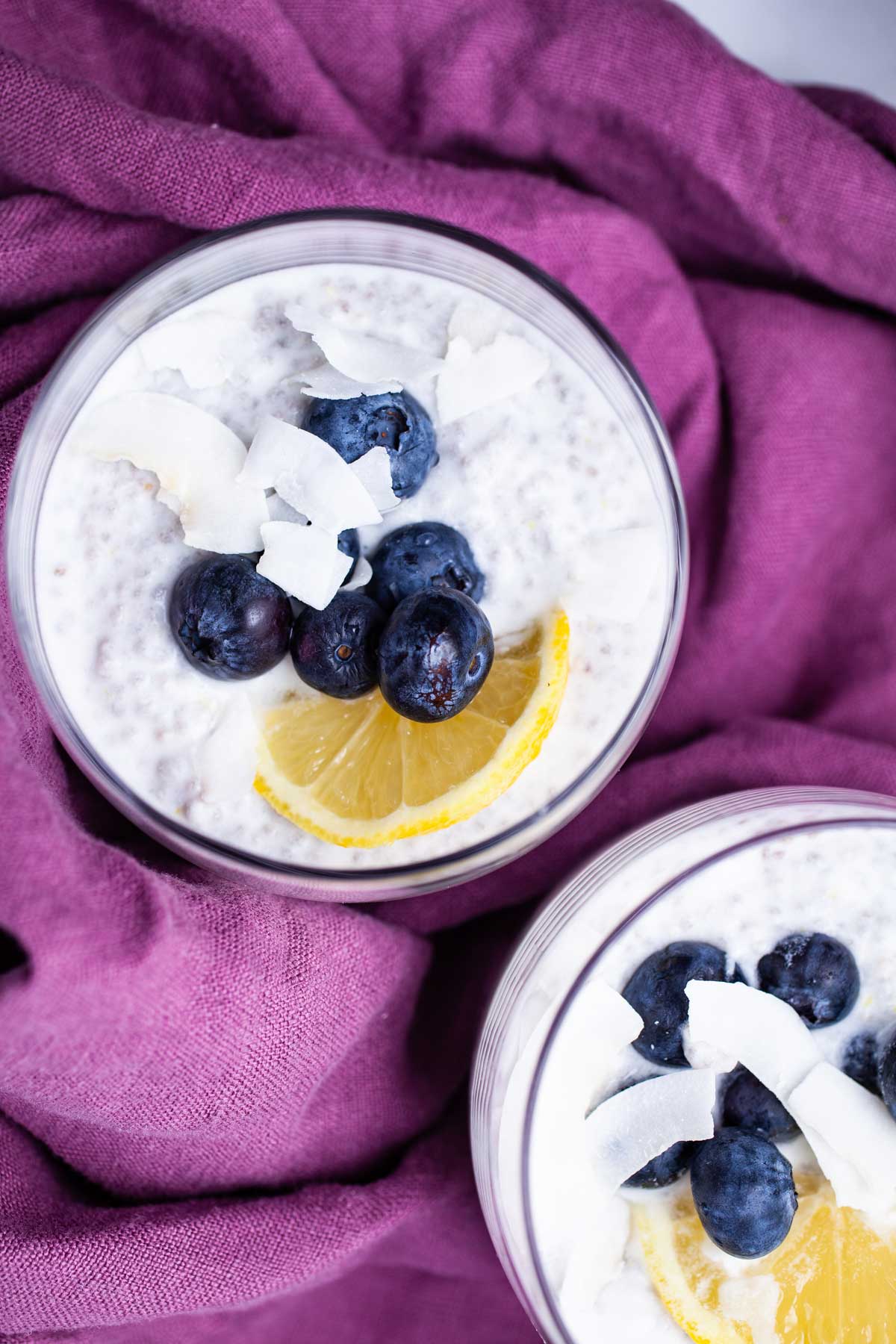 Two cups filled with lemon chia pudding topped with blueberries.