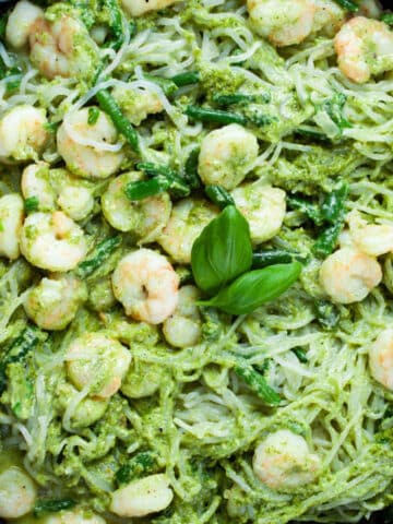 Shrimp with Shirataki noodles tossed in a green pesto sauce and presented in a large skillet.