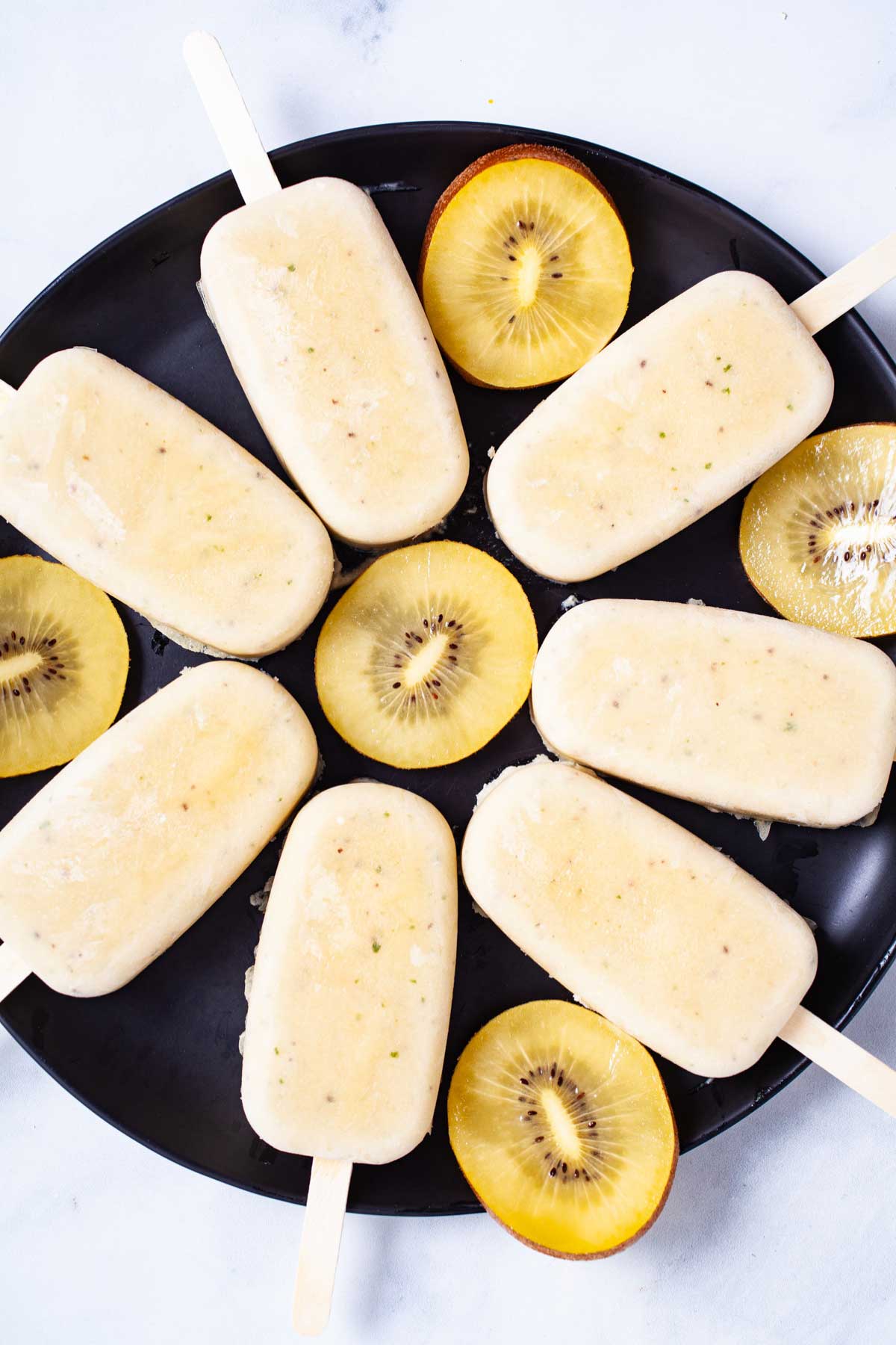 Healthy kiwi popsicles presented on a plate.
