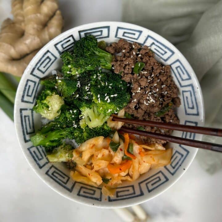 an overhead shot of korean bison bowls with ground bison, broccoli and pickled vegetables topped with sesame seeds.