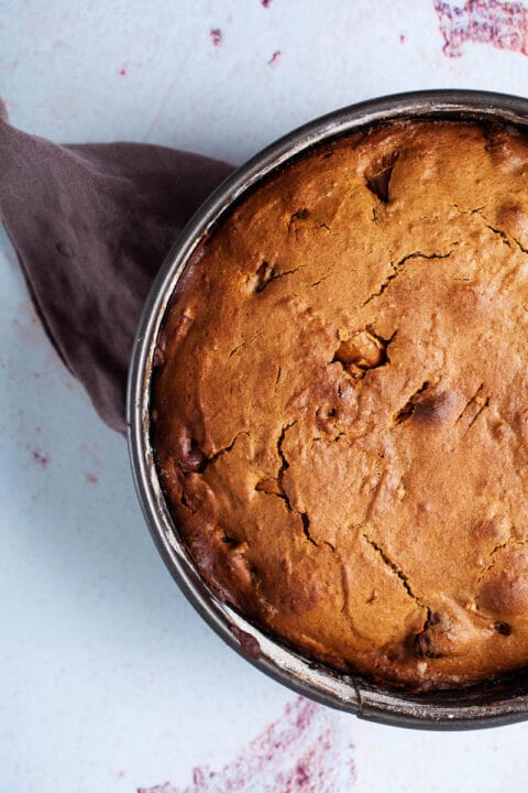 A brown coffee cake in a cake pan displayed on a table.