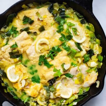 Creamy cooked cod and leek in a cast iron pan.