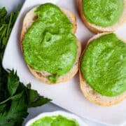 Green parsley and anchovy paste spread on little toast on a plate.