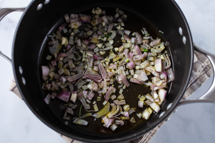 A pot with olive oil, chopped garlic and shallots.