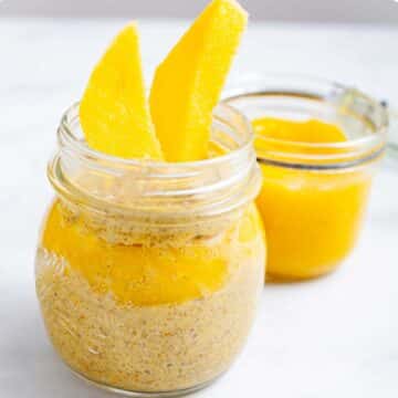 Mango coconut chia pudding served in a glass jar with mango sauce on the side.