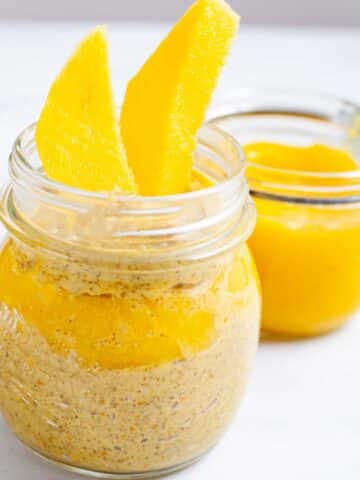 Mango coconut chia pudding served in a glass jar with mango sauce on the side.