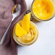 Mango coconut chia pudding served in a glass jar with mango sauce on the side.