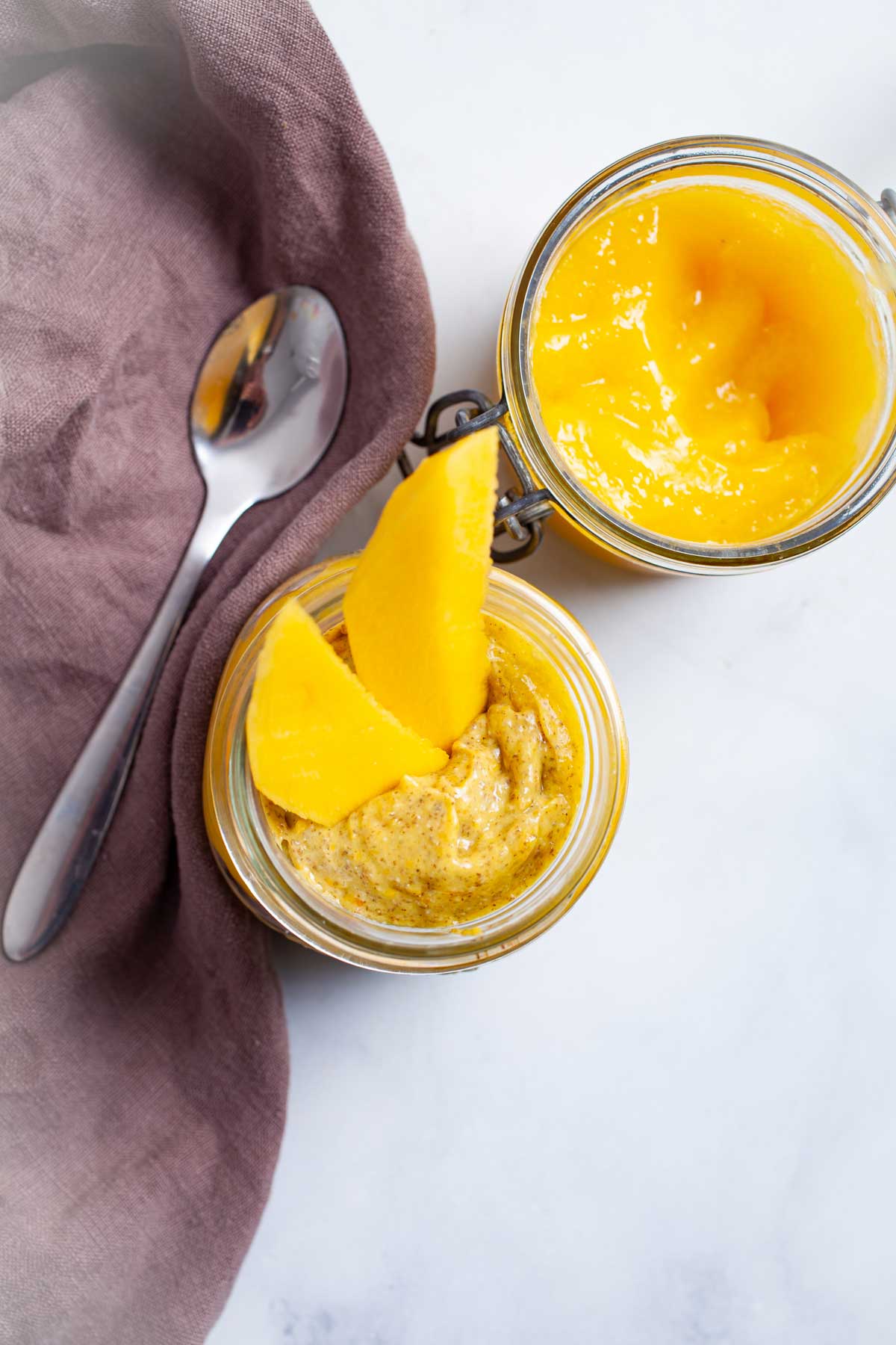 Mango coconut chia pudding served in a glass jar with mango sauce on the side.