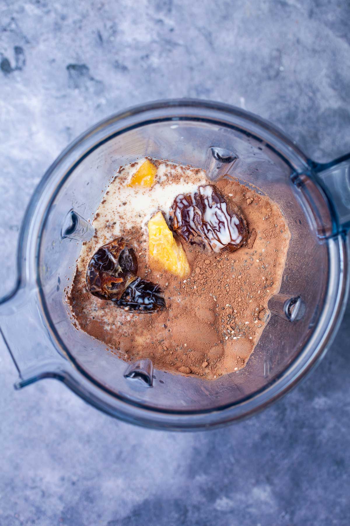 Oat milk, cacao powder, dates, chia seeds and mangoes in a blender.