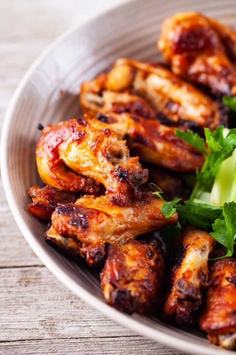 A close up of plate filled with baked chicken wings and thighs.