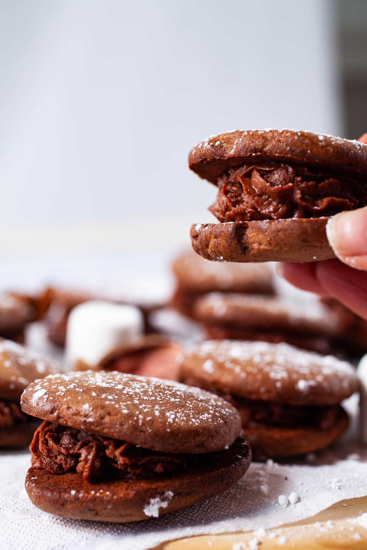 a hand holding a mascarpone filled sandwich cookie.