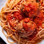 A plate with spaghetti noodles, and topped with a red Italian spaghetti sauce and juicy meatballs.