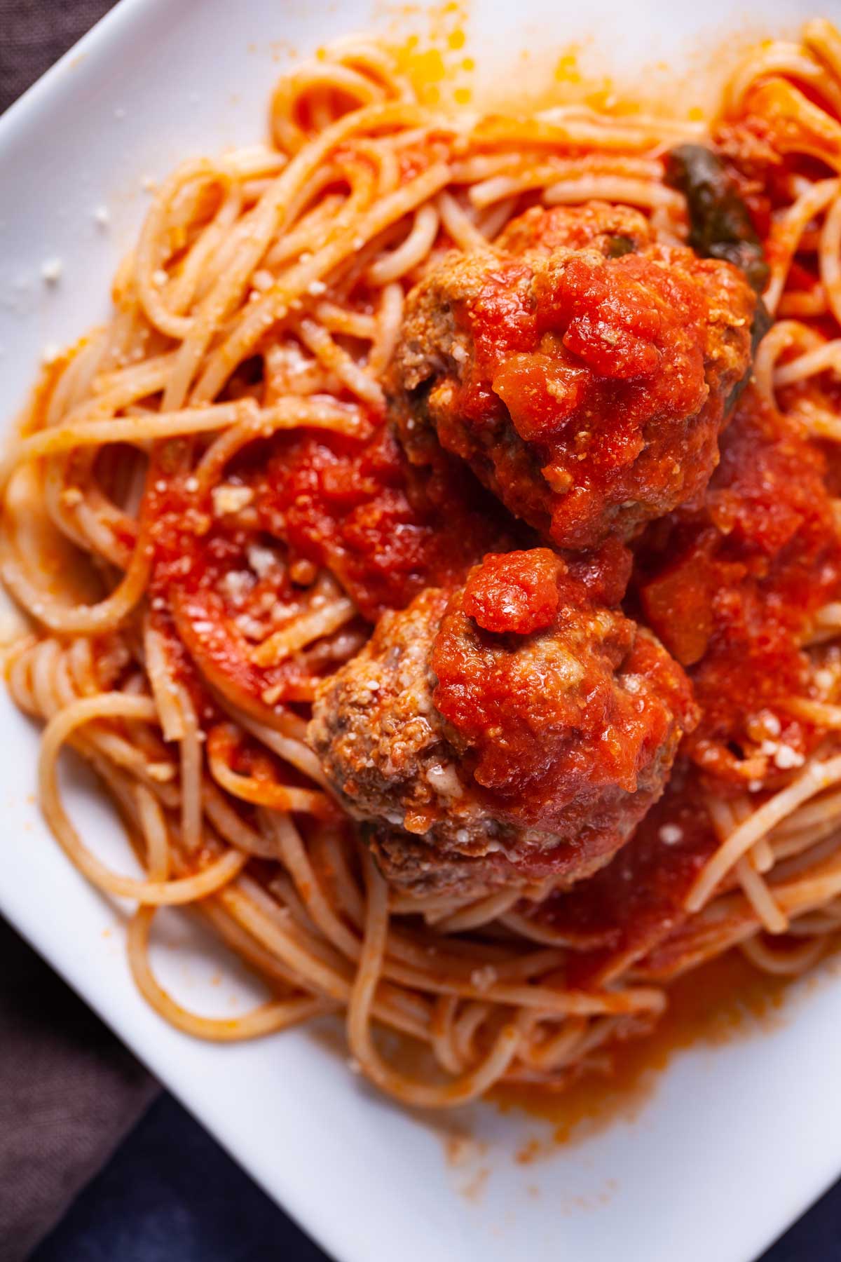 A plate with spaghetti noodles, and topped with a red Italian spaghetti sauce and juicy meatballs.