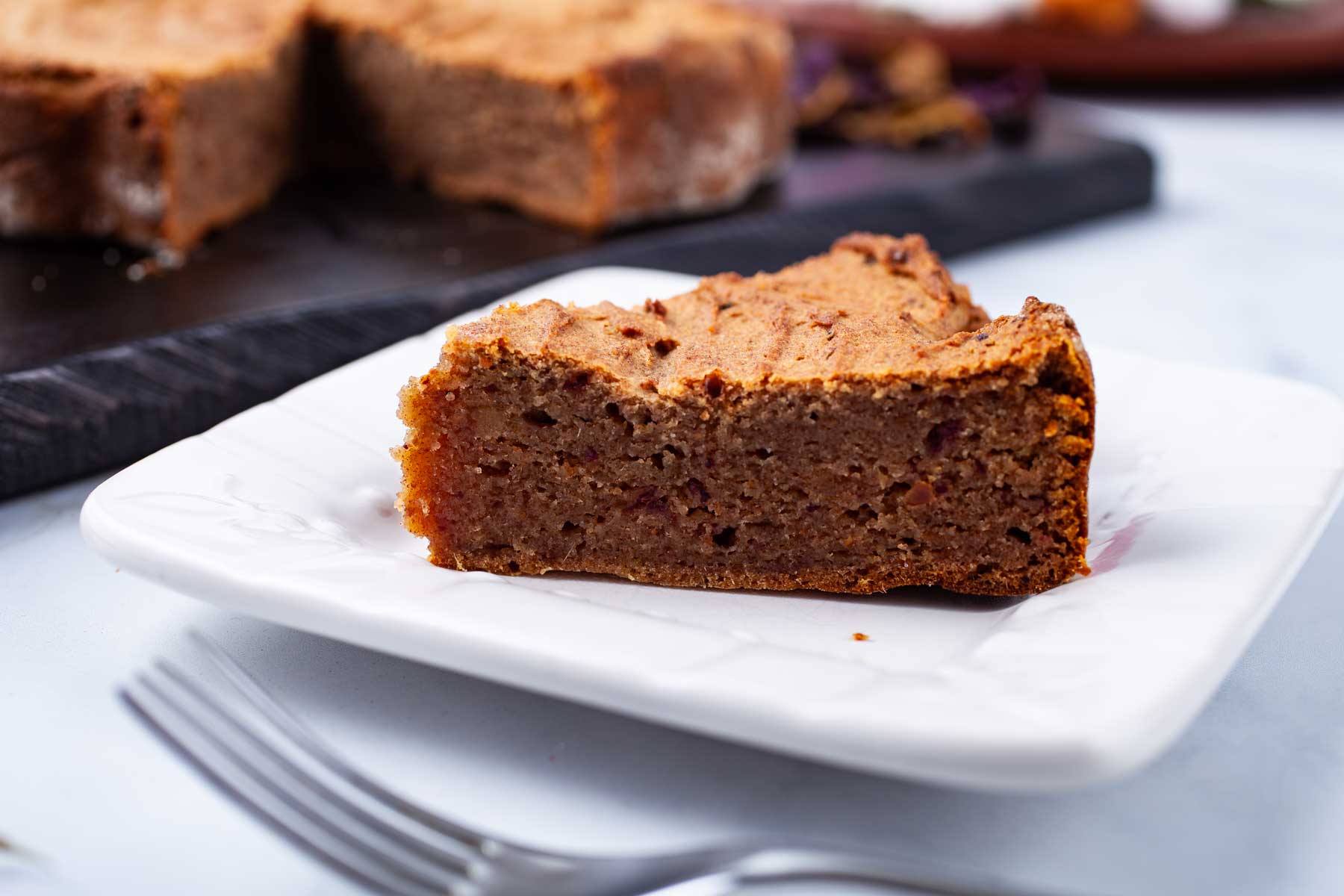 A piece of a date cake on a small serving plate.