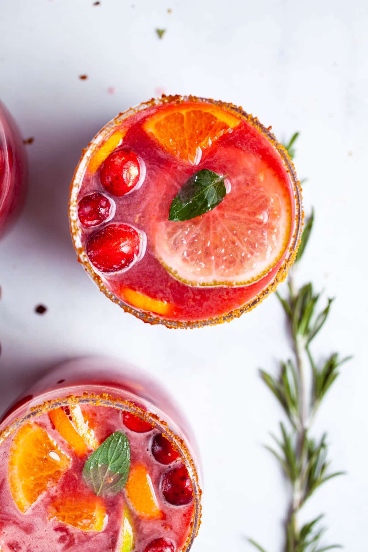 A close up of a pomegranate drink garnished with fresh fruits and mint displayed on a table.