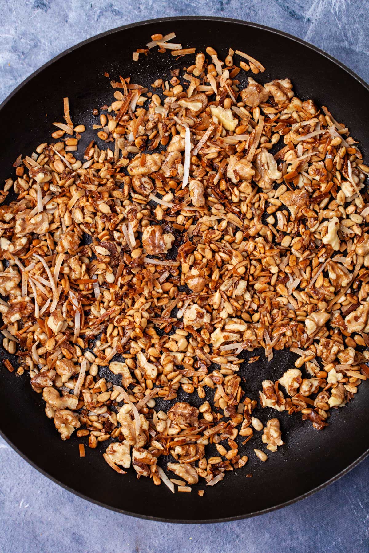 Toasted nuts, seeds, and coconut shreds in a skillet.