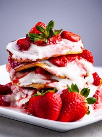 Pancakes stacked on top of each other and topped with strawberries and goat yogurt.