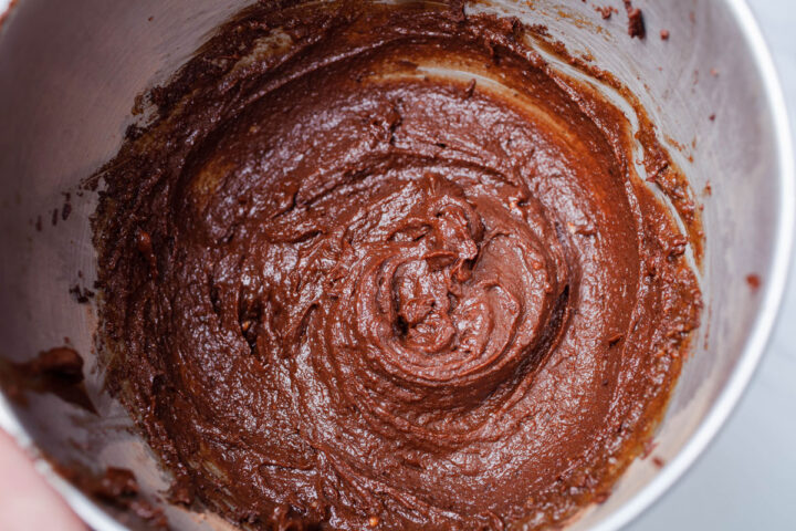 Brown cookie batter in a stainless steel bowl.