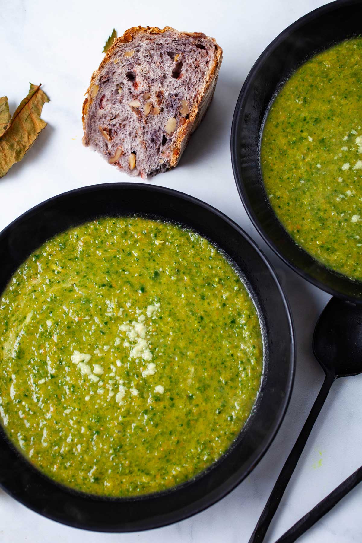 Bowls of no cream asparagus soup served with rustic bread on the side.