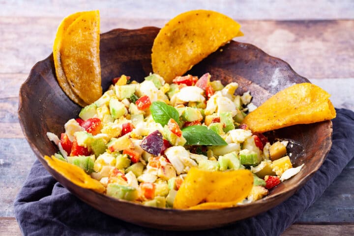 A bowl filled with a non-traditional egg salad and tacos served on the side.