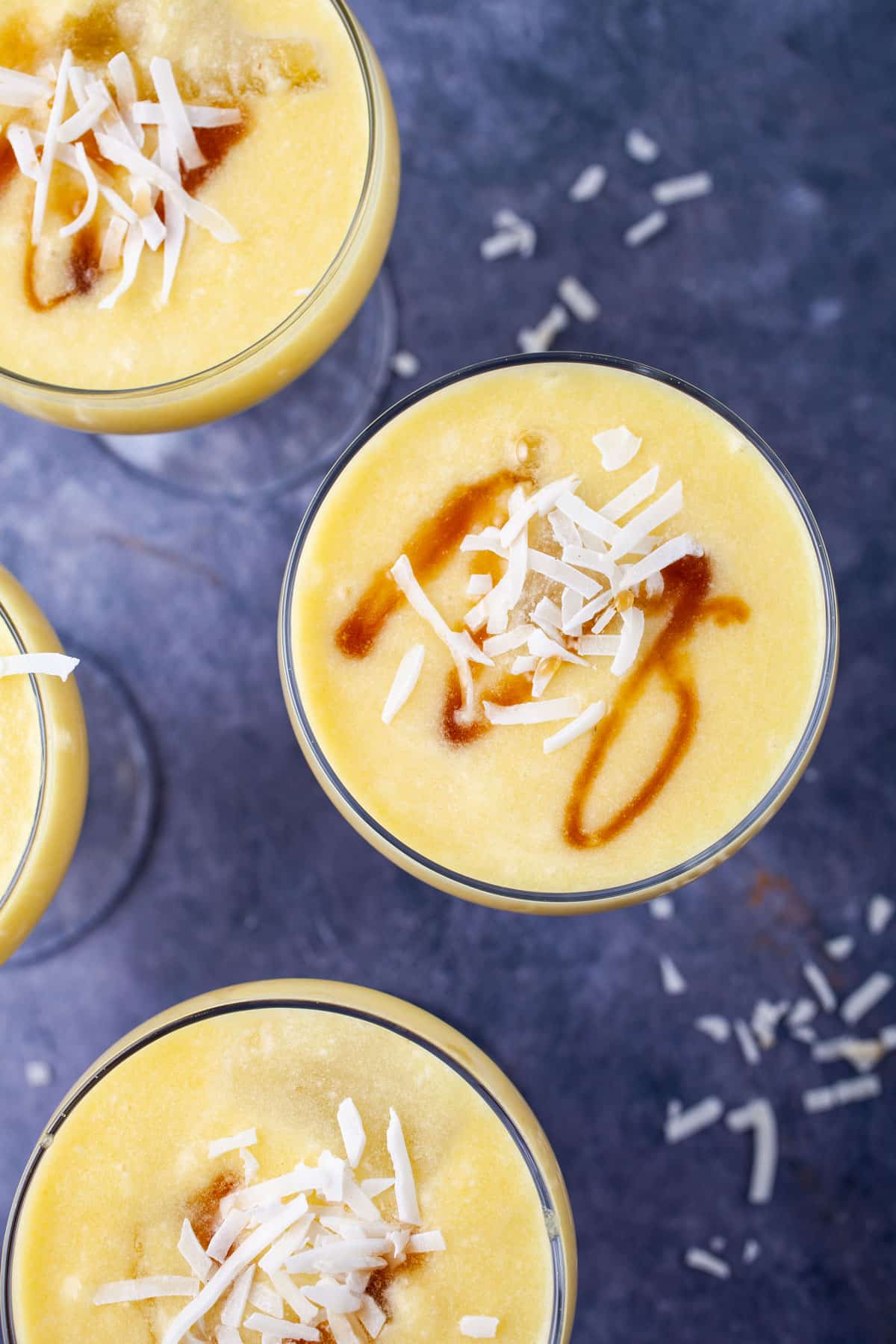 Pina colada non alcoholic drinks garnished with coconut shreds and a drizzle of maple syrup.
