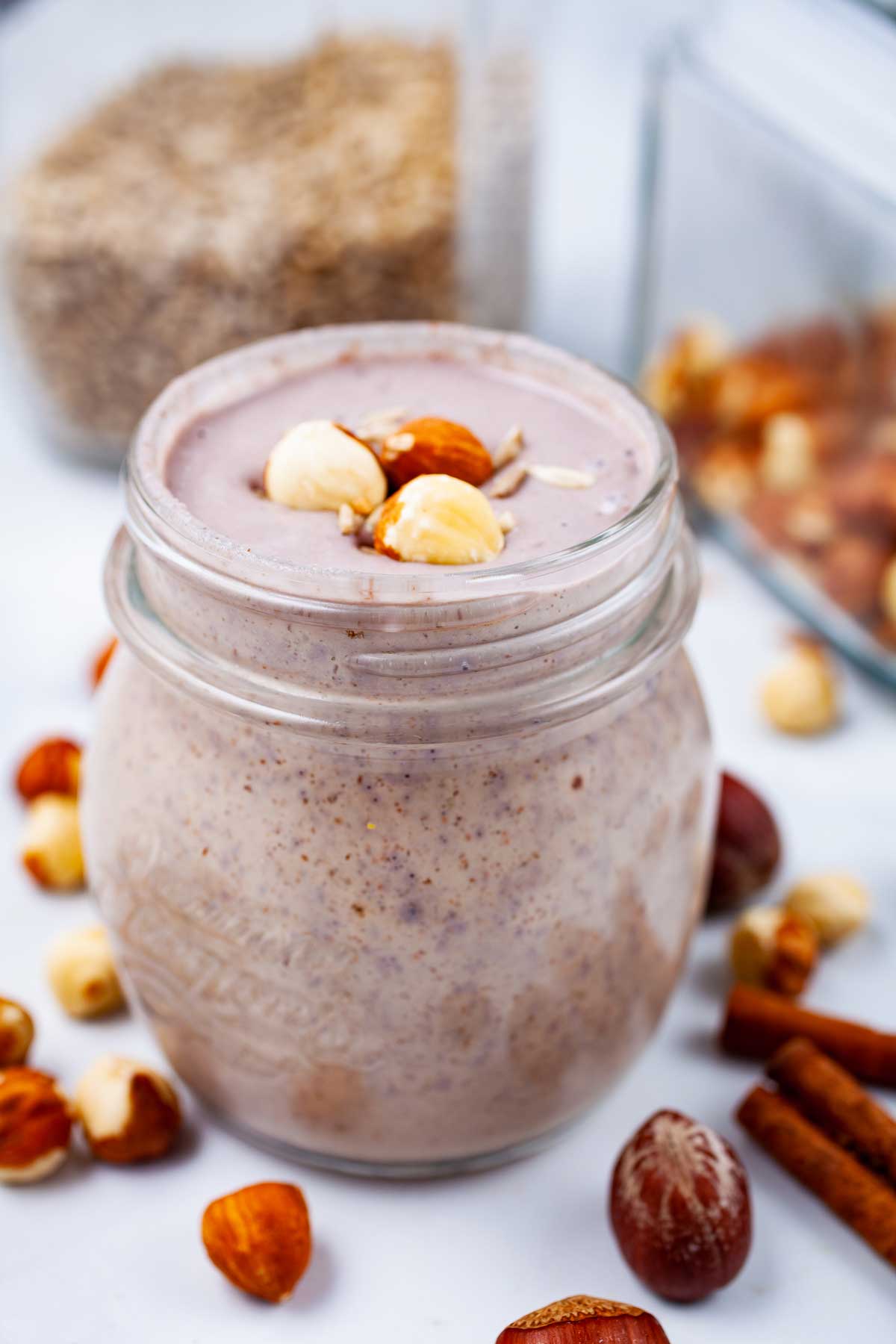 A creamy nut smoothie on a table, garnished with hazelnuts.
