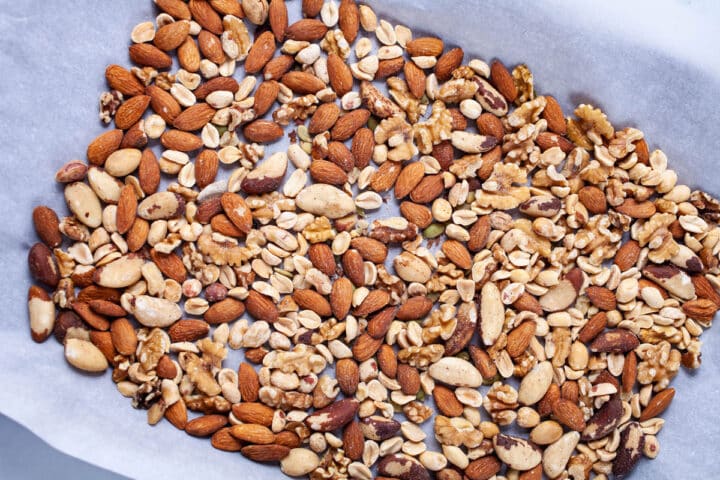 A mix of nuts spread out on a prepared baking sheet.