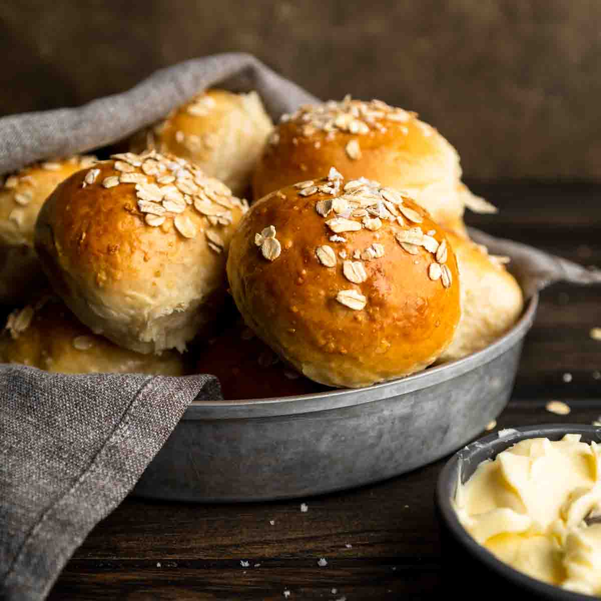 Homemade dinner rolls in a bowl and half covered with a napkin.