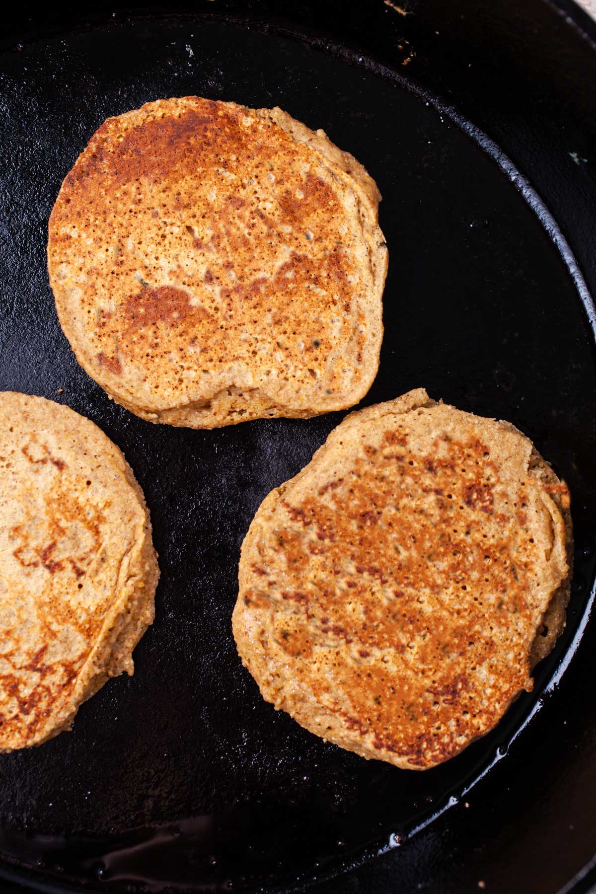 Three pancakes in a cast-iron pan.